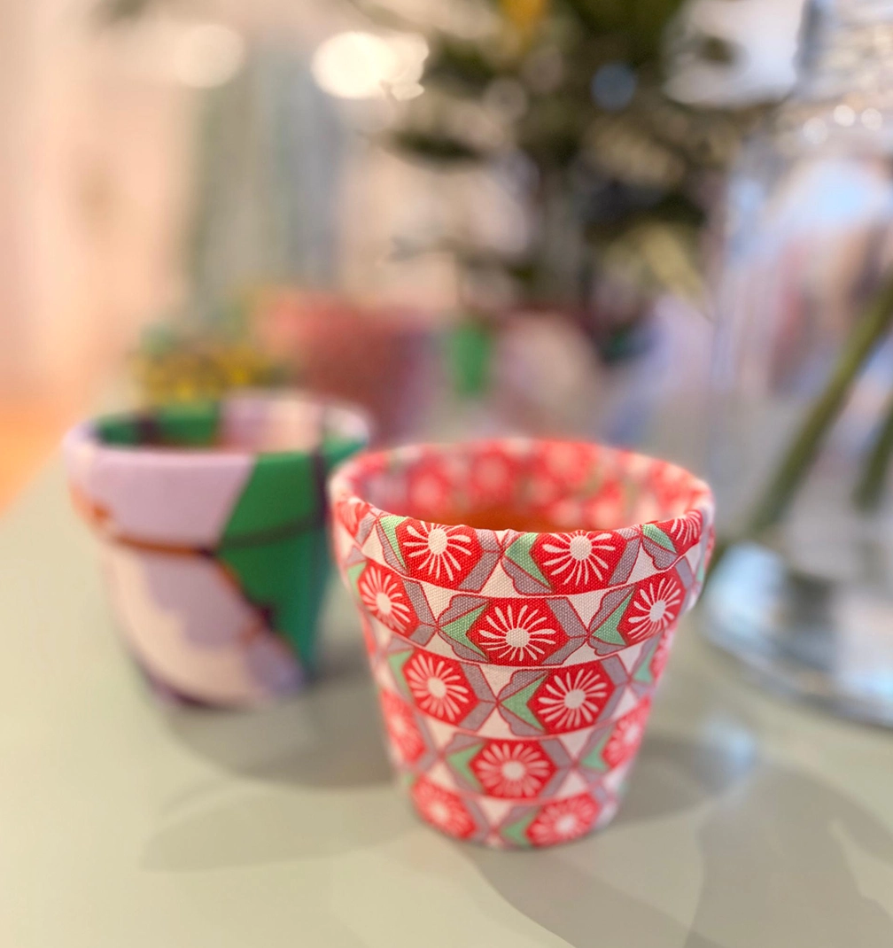 pot-new-3 A little pot covered in red and white geometric flower fabric, with a lilac and green pot behind it.